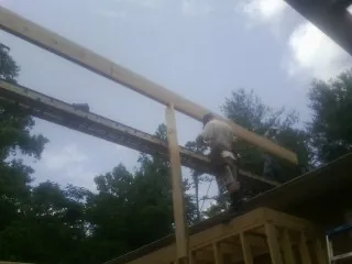 Carpenter setting a ridge beam over a new addition frame — Ice Dam Removal by Roofing Brothers in South Gardiner