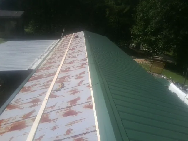 Old rusted panels beside newly installed green metal roofing — Wind Damage Roof Repair by Roofing Brothers in South Gardiner