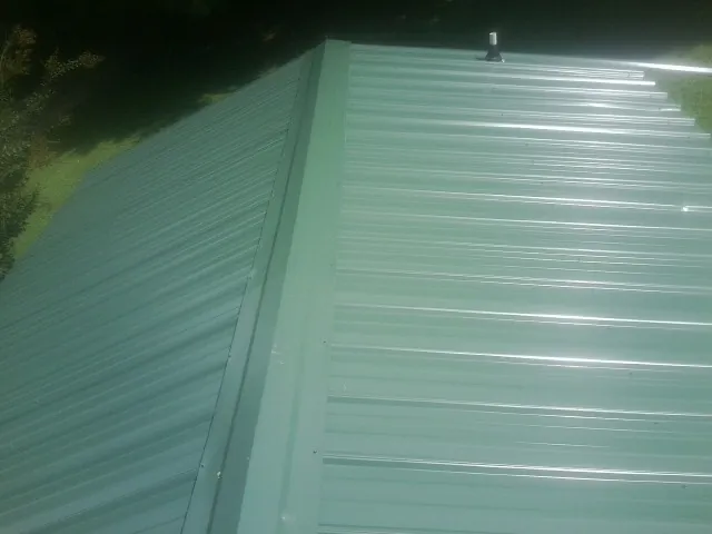 New green metal panels meeting at the ridge of a roof — Flat Roof Repair work by our crew in South Gardiner