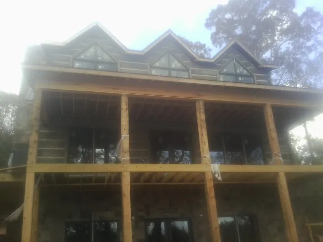 Dormers and porch framing on a large log home under construction — Roof Coating work by our crew in South Gardiner