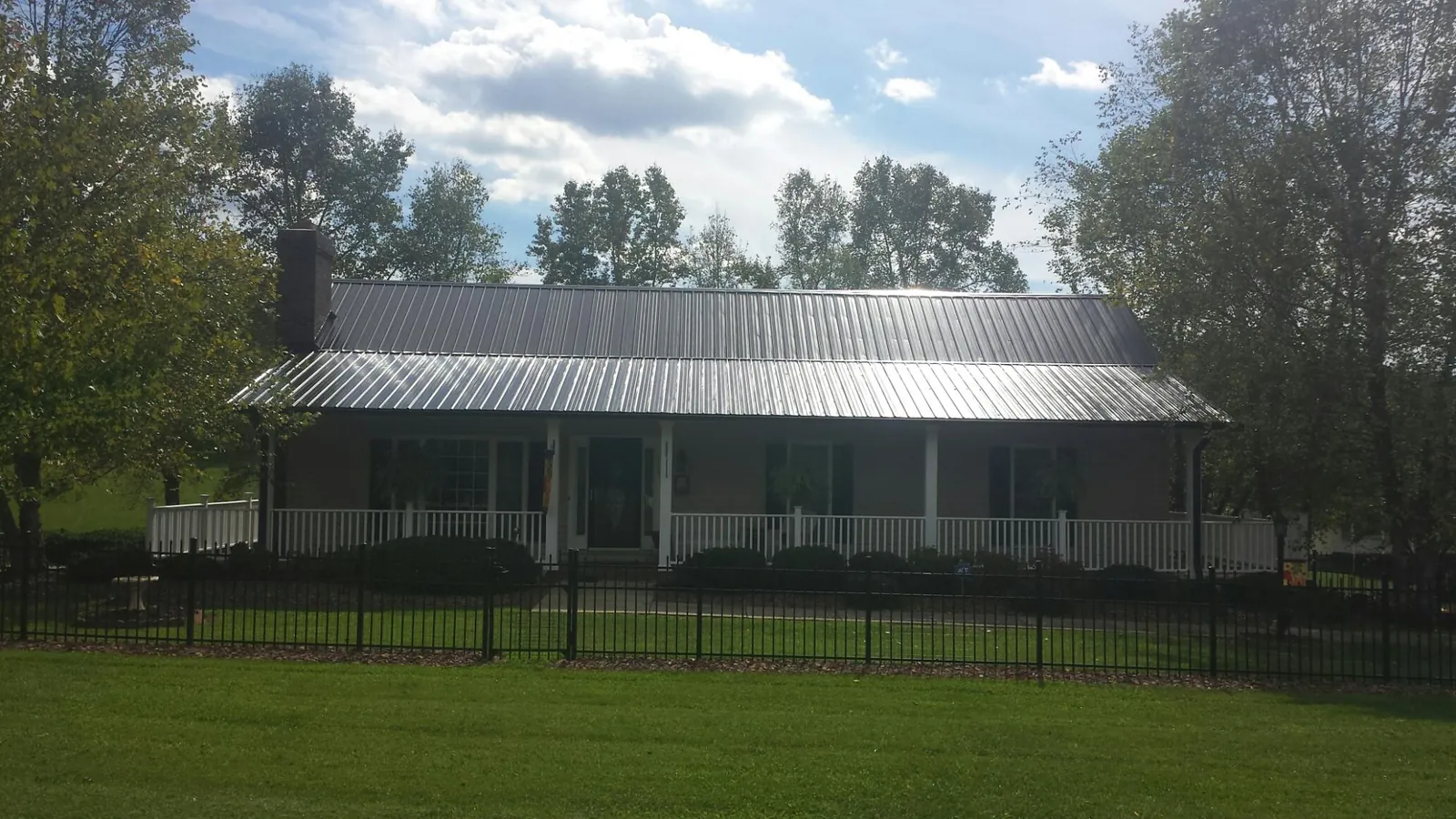 Gray metal roof on a brick ranch with a full width front porch — Gutter Guard Installation work by our crew in South Gardiner