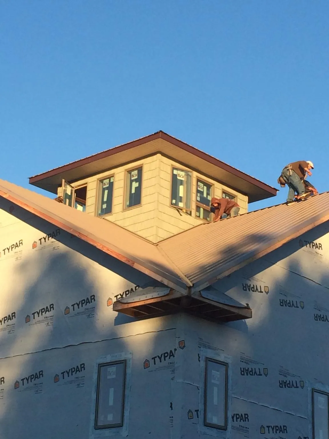 Roofers working around a rooftop cupola on a new metal roof at sunset — Roof Waterproofing in South Gardiner by Roofing Brothers